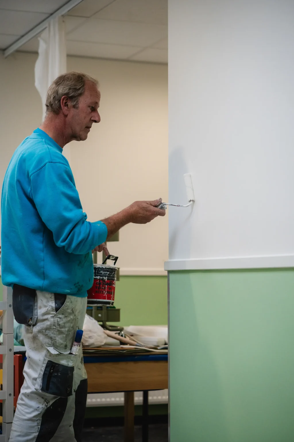 Schilder van Van Foeken rolt rustig een wand in een gang
