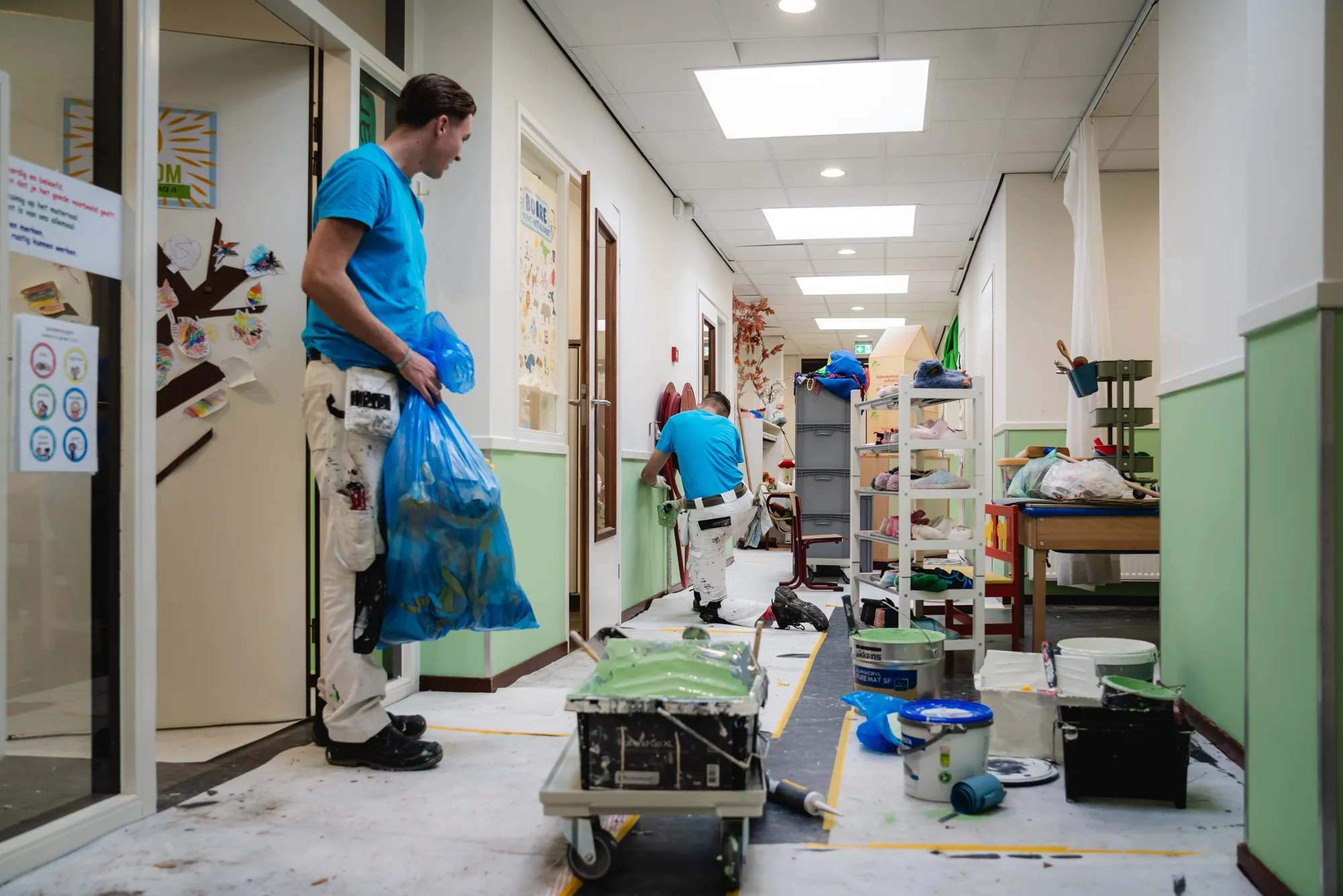 Schilders van Van Foeken aan het werk in een gang, looproute vrijgehouden