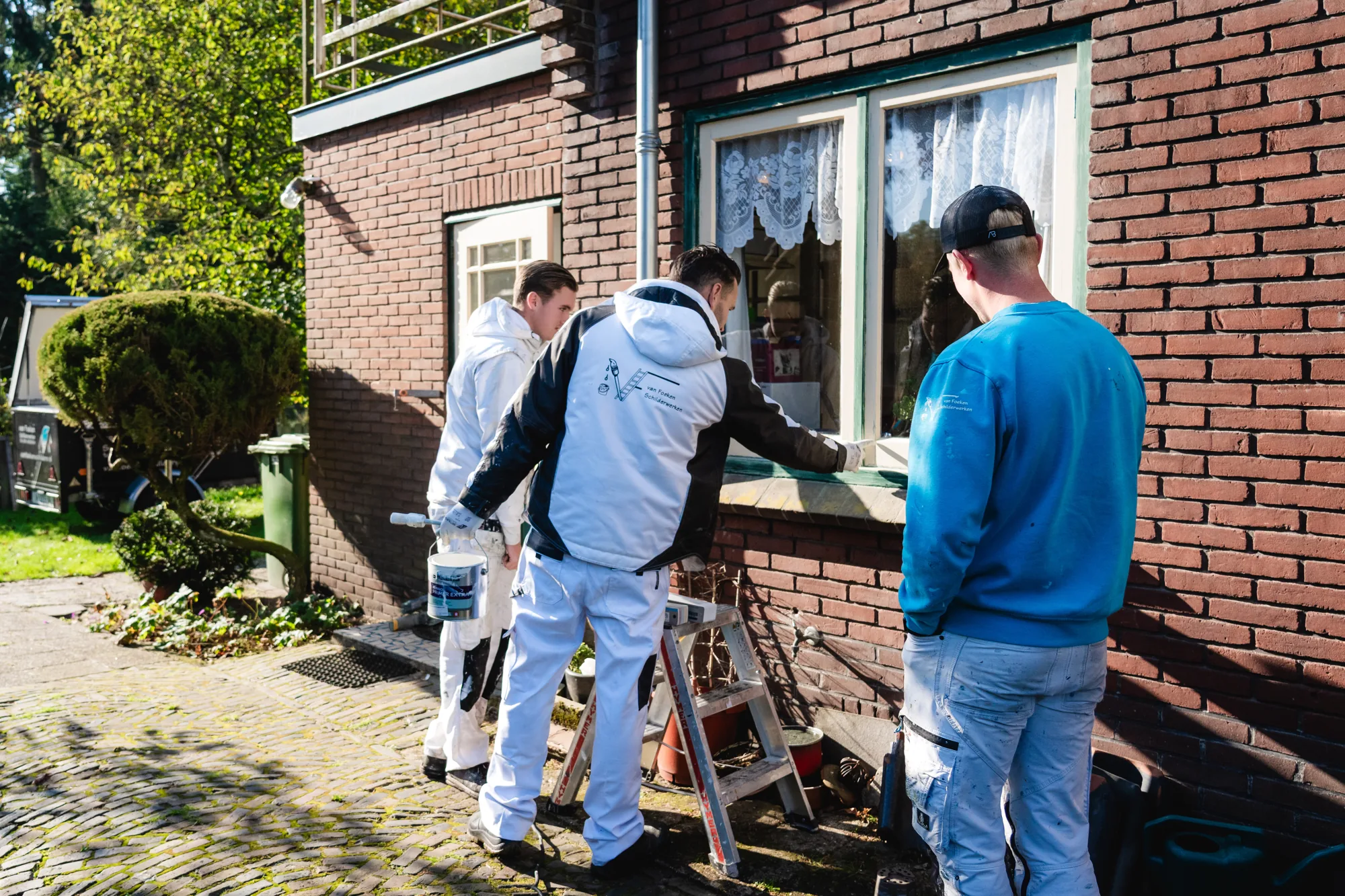Twee schilders van Van Foeken bij de kozijnen van een woning